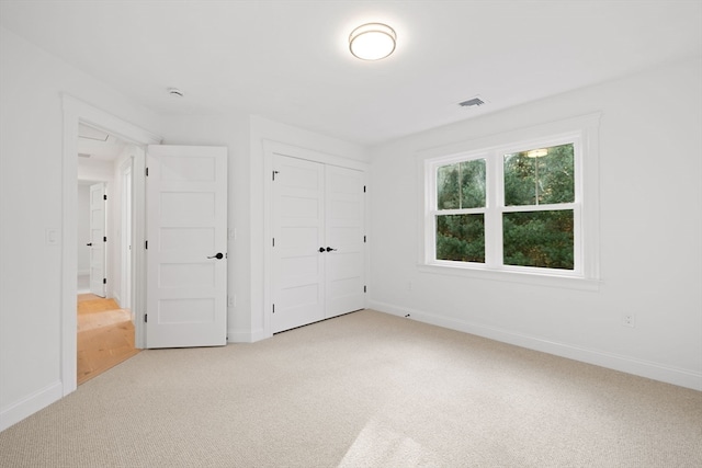 unfurnished bedroom featuring light colored carpet and a closet