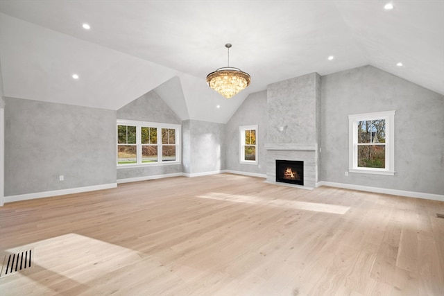 unfurnished living room featuring a large fireplace, light hardwood / wood-style floors, an inviting chandelier, and vaulted ceiling