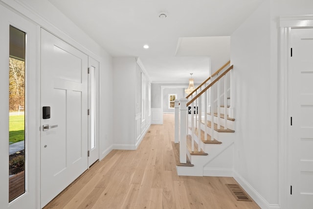 entryway with light hardwood / wood-style floors, a wealth of natural light, and a chandelier