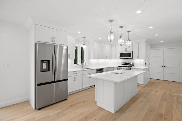 kitchen featuring stainless steel appliances, sink, light hardwood / wood-style flooring, a center island, and hanging light fixtures