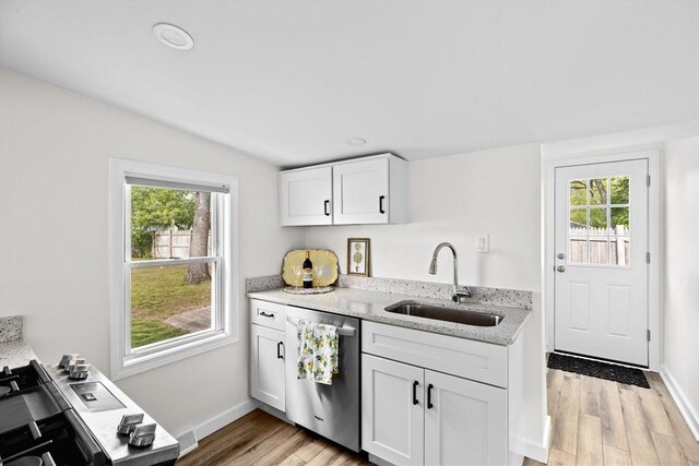 216 Waltham St, Hanson, MA 02341 - kitchen featuring stainless steel dishwasher, a sink, light wood-type flooring, light stone counters, and healthy amount of natural light