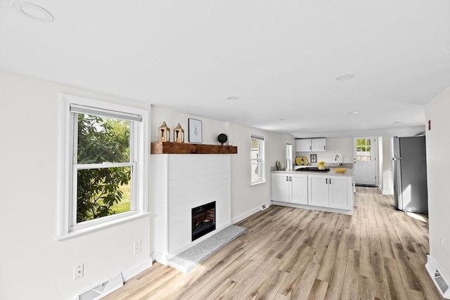 216 Waltham St, Hanson, MA 02341 - unfurnished living room with light wood-style floors, baseboards, a fireplace with raised hearth, and recessed lighting