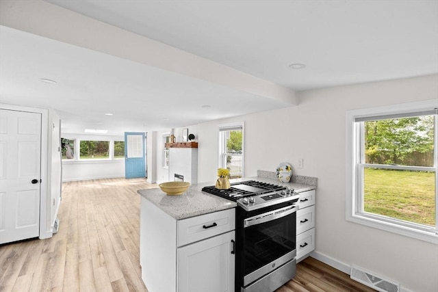 216 Waltham St, Hanson, MA 02341 - kitchen featuring stainless steel gas range oven, light wood-style floors, plenty of natural light, and light stone countertops