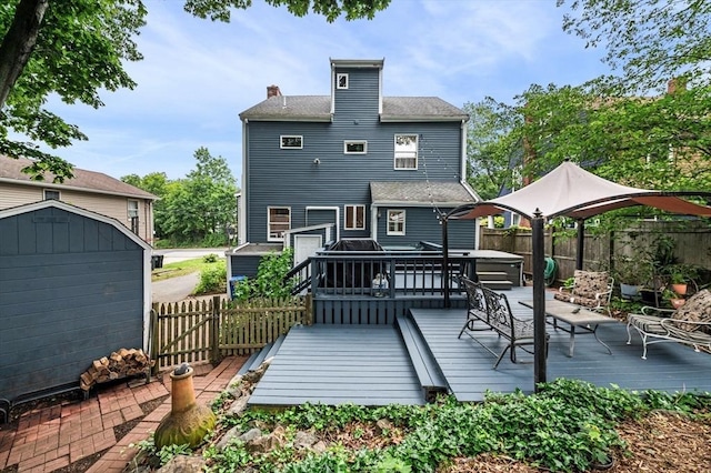 31 Cedar Hill Ter, Swampscott, MA 01907 - back of property with a storage unit, a fenced backyard, a deck, outdoor dining space, and a chimney