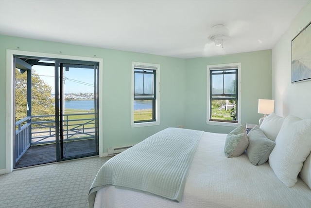 carpeted bedroom with baseboards, access to exterior, a water view, and a baseboard heating unit