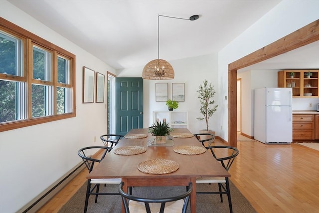 dining area with a baseboard radiator, a notable chandelier, baseboards, and light wood-type flooring