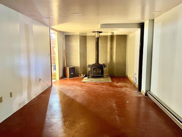 living area with concrete floors, a wood stove, and baseboard heating
