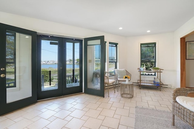 sitting room with recessed lighting, a water view, and french doors