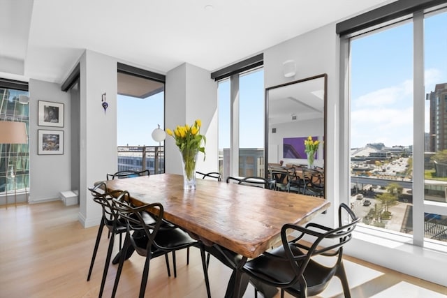 dining area featuring light wood-type flooring and expansive windows