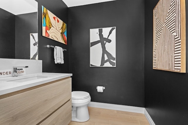 bathroom with wood-type flooring, vanity, and toilet