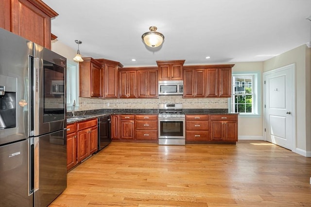 44 Sachem St, Waltham, MA 02451 - kitchen with appliances with stainless steel finishes, light wood-style floors, tasteful backsplash, baseboards, and brown cabinets