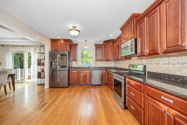 44 Sachem St, Waltham, MA 02451 - kitchen with stainless steel appliances, light wood finished floors, decorative backsplash, brown cabinetry, and a sink