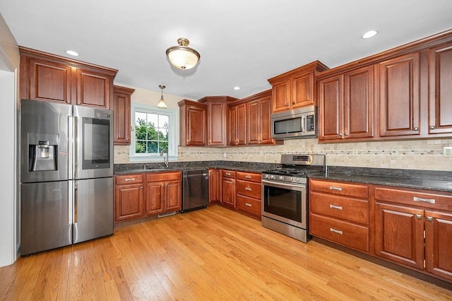 44 Sachem St, Waltham, MA 02451 - kitchen featuring stainless steel appliances, a sink, light wood-type flooring, backsplash, and hanging light fixtures