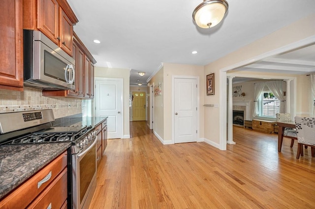 44 Sachem St, Waltham, MA 02451 - kitchen featuring appliances with stainless steel finishes, light wood-style flooring, decorative backsplash, baseboards, and a fireplace