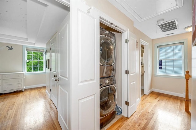 44 Sachem St, Waltham, MA 02451 - laundry room featuring stacked washer / drying machine, attic access, light wood-style floors, and baseboards