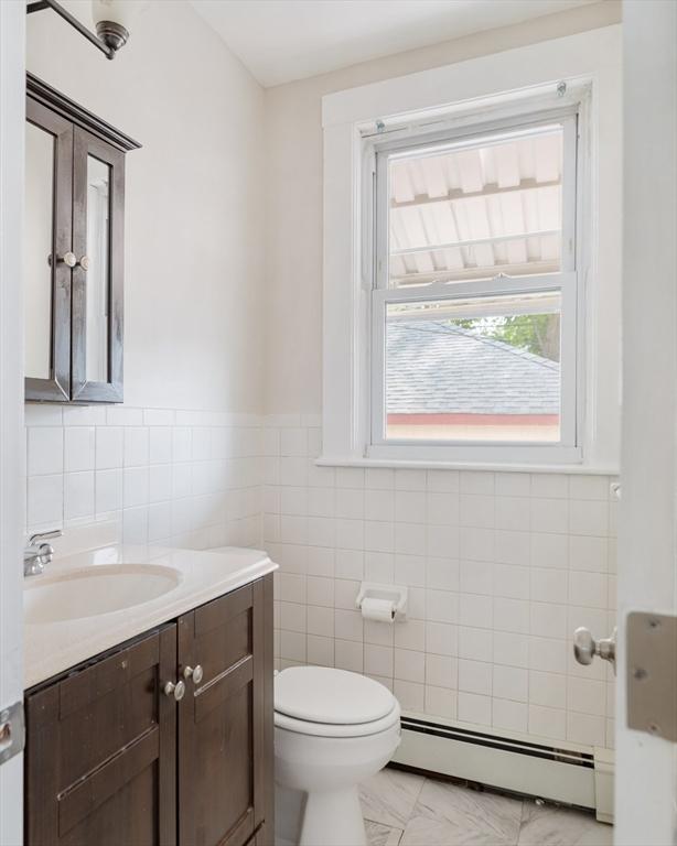 204 Maple St, Boston, MA 02132 - half bathroom with a baseboard heating unit, tile walls, vanity, and wainscoting