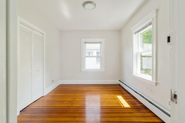 204 Maple St, Boston, MA 02132 - unfurnished bedroom with baseboard heating, multiple windows, wood finished floors, and a closet