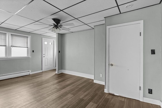 unfurnished room with a baseboard heating unit, a drop ceiling, dark wood-type flooring, and ceiling fan