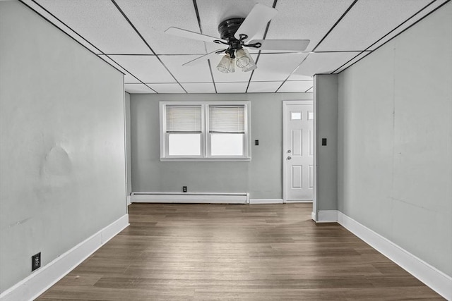 empty room featuring a paneled ceiling, ceiling fan, dark hardwood / wood-style flooring, and a baseboard radiator