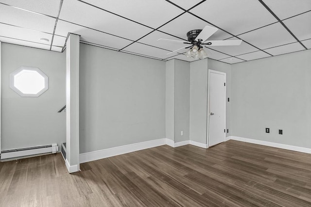 basement with a paneled ceiling, ceiling fan, a baseboard radiator, and hardwood / wood-style flooring