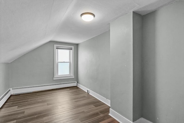 additional living space with dark hardwood / wood-style flooring, a baseboard radiator, and lofted ceiling