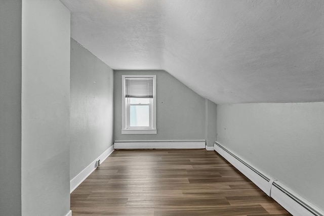 bonus room with vaulted ceiling, baseboard heating, and dark wood-type flooring