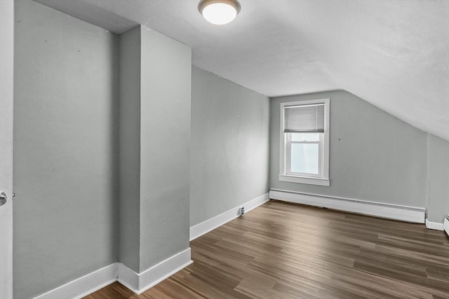 bonus room featuring dark hardwood / wood-style floors, vaulted ceiling, and a baseboard heating unit