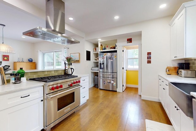 12 Lester Ter, Somerville, MA 02144 - kitchen with stainless steel appliances, island range hood, plenty of natural light, white cabinetry, and recessed lighting