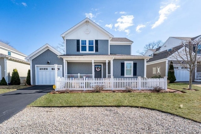 view of front of property with a fenced front yard, covered porch, driveway, and an attached garage