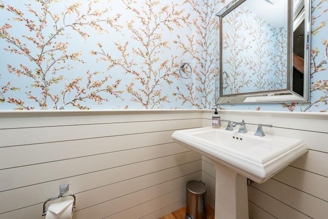 bathroom with wainscoting and wallpapered walls