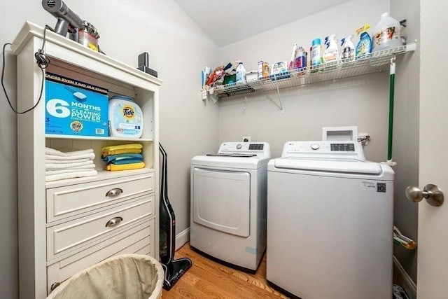 clothes washing area with light wood-type flooring, laundry area, and separate washer and dryer