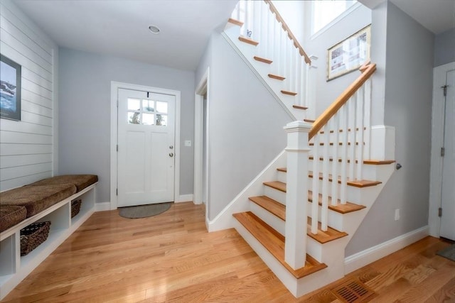 entrance foyer with visible vents, light wood-style flooring, baseboards, and stairs