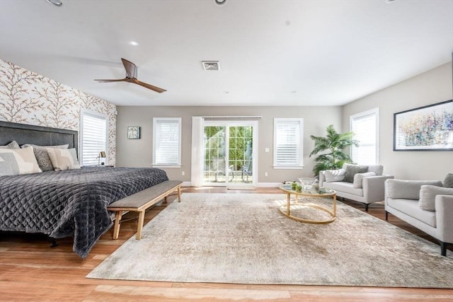 bedroom with access to outside, wood finished floors, visible vents, and multiple windows