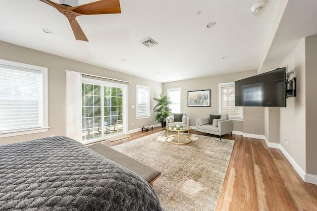 bedroom featuring access to exterior, multiple windows, visible vents, and wood finished floors