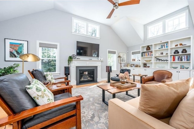 living area featuring high vaulted ceiling, light wood-type flooring, a fireplace with flush hearth, and a healthy amount of sunlight