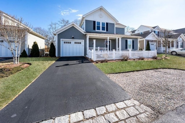 view of front facade with aphalt driveway, a porch, fence, a garage, and a front lawn