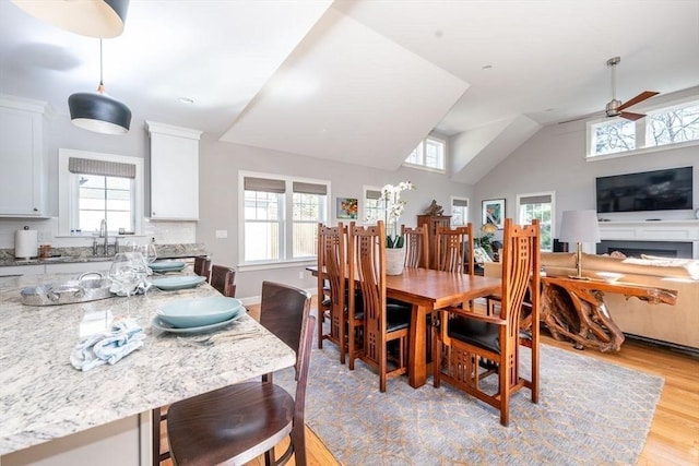 dining space featuring lofted ceiling, light wood-type flooring, a ceiling fan, and baseboards