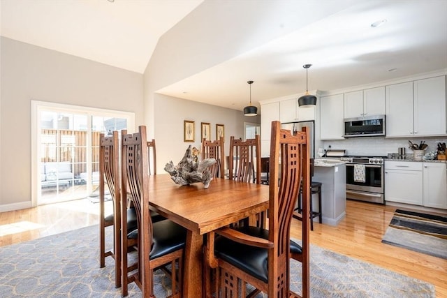 dining space with light wood-type flooring, vaulted ceiling, and baseboards