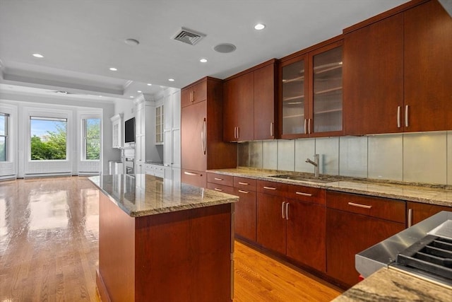 316 Beacon St Unit 1, Boston, MA 02116 - kitchen with light wood finished floors, glass insert cabinets, a center island, a raised ceiling, and recessed lighting
