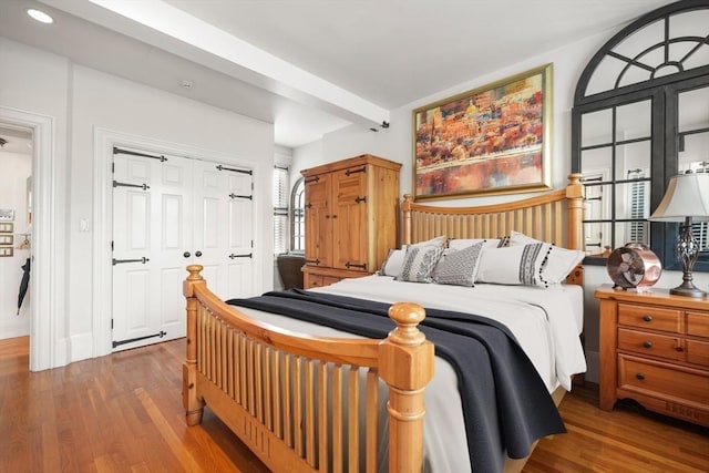 bedroom featuring beamed ceiling, dark hardwood / wood-style floors, and a closet