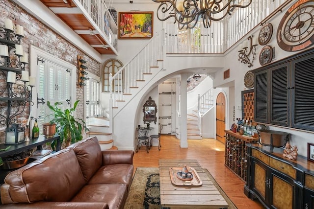 living room with a towering ceiling, a chandelier, and light wood-type flooring