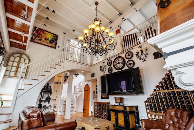 living room featuring beamed ceiling, a high ceiling, a notable chandelier, and wood ceiling