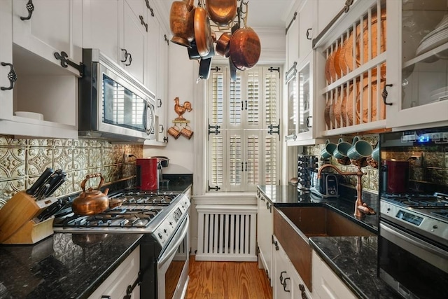 kitchen with white cabinetry, appliances with stainless steel finishes, dark stone countertops, and decorative backsplash