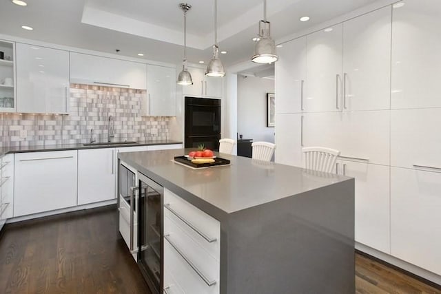 kitchen with white cabinets, a spacious island, and sink