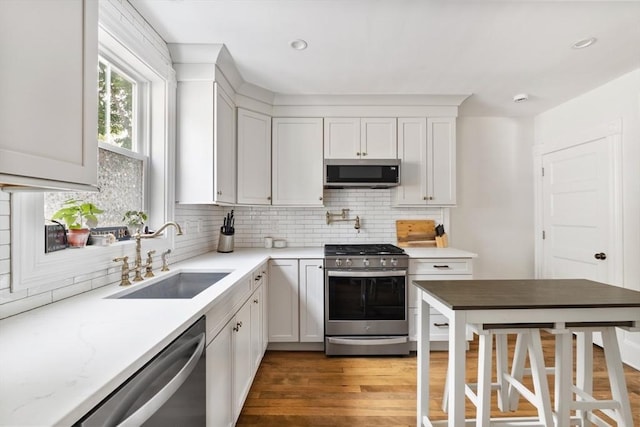 59-61 Elm St, Andover, MA 01810 - kitchen featuring appliances with stainless steel finishes, decorative backsplash, wood finished floors, white cabinets, and recessed lighting