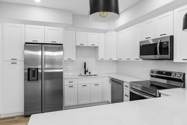 kitchen with decorative backsplash, stainless steel appliances, white cabinetry, and sink