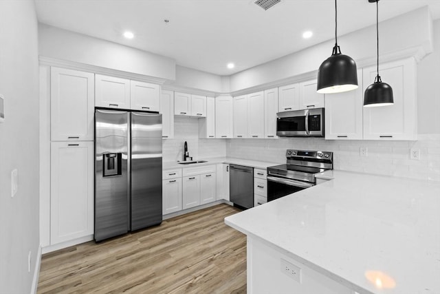 kitchen with white cabinetry, sink, stainless steel appliances, light hardwood / wood-style flooring, and pendant lighting