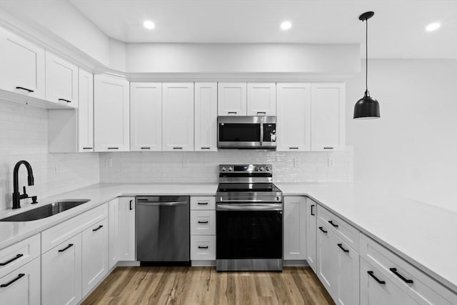 kitchen with white cabinets, stainless steel appliances, hanging light fixtures, and sink