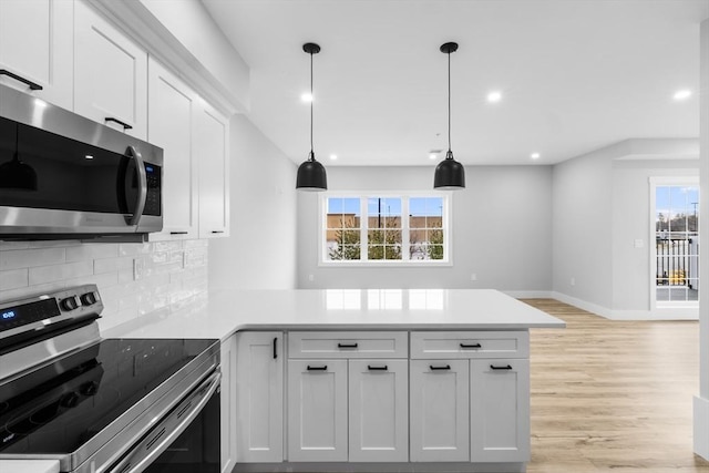 kitchen featuring white cabinets, kitchen peninsula, hanging light fixtures, and appliances with stainless steel finishes