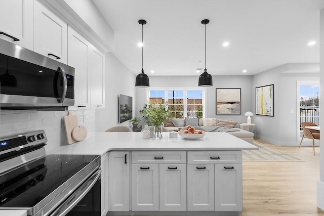 kitchen with white cabinets, appliances with stainless steel finishes, decorative light fixtures, and tasteful backsplash